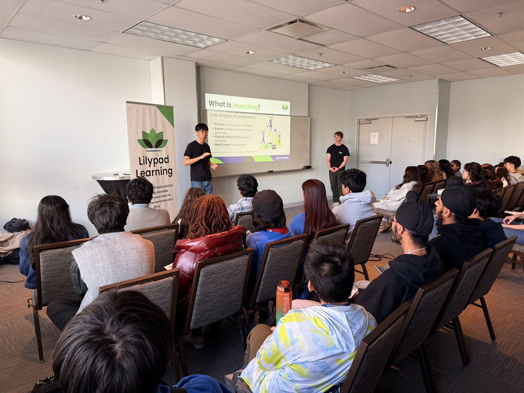 Two Lilypad Learning educators presenting an investing lesson to a full room of youth